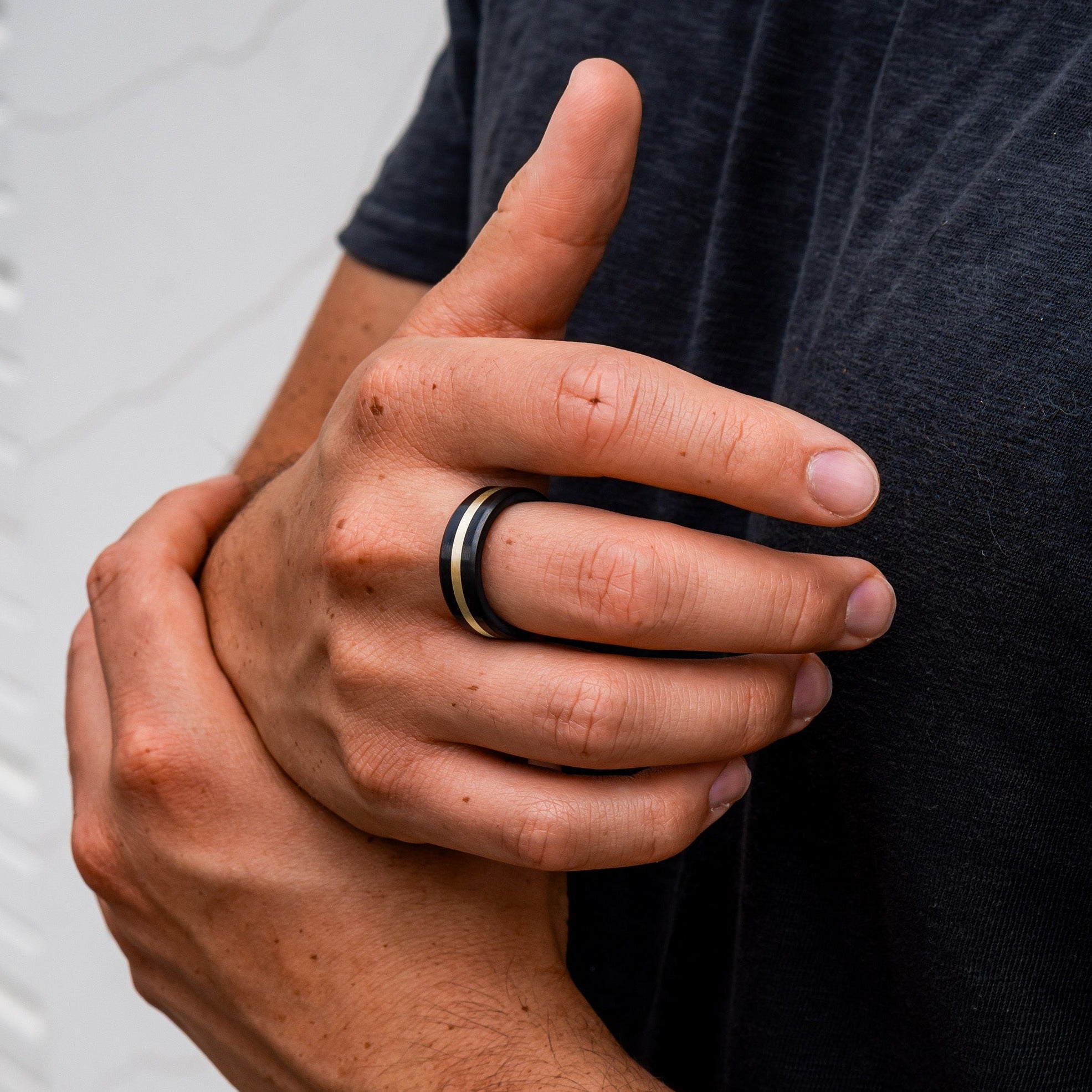 Lifestyle shot #2 of men's hands wearing our Elysium ARES Men's Black Diamond & 14k Yellow Gold Inlay | ElysiumBlack.com | Men’s 14k Yellow Gold Inlay Wedding Rings